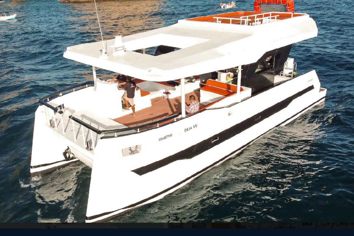 Aerial view of a 60 foot event catamaran cruising blue water in Cabo San Lucas with guests on deck