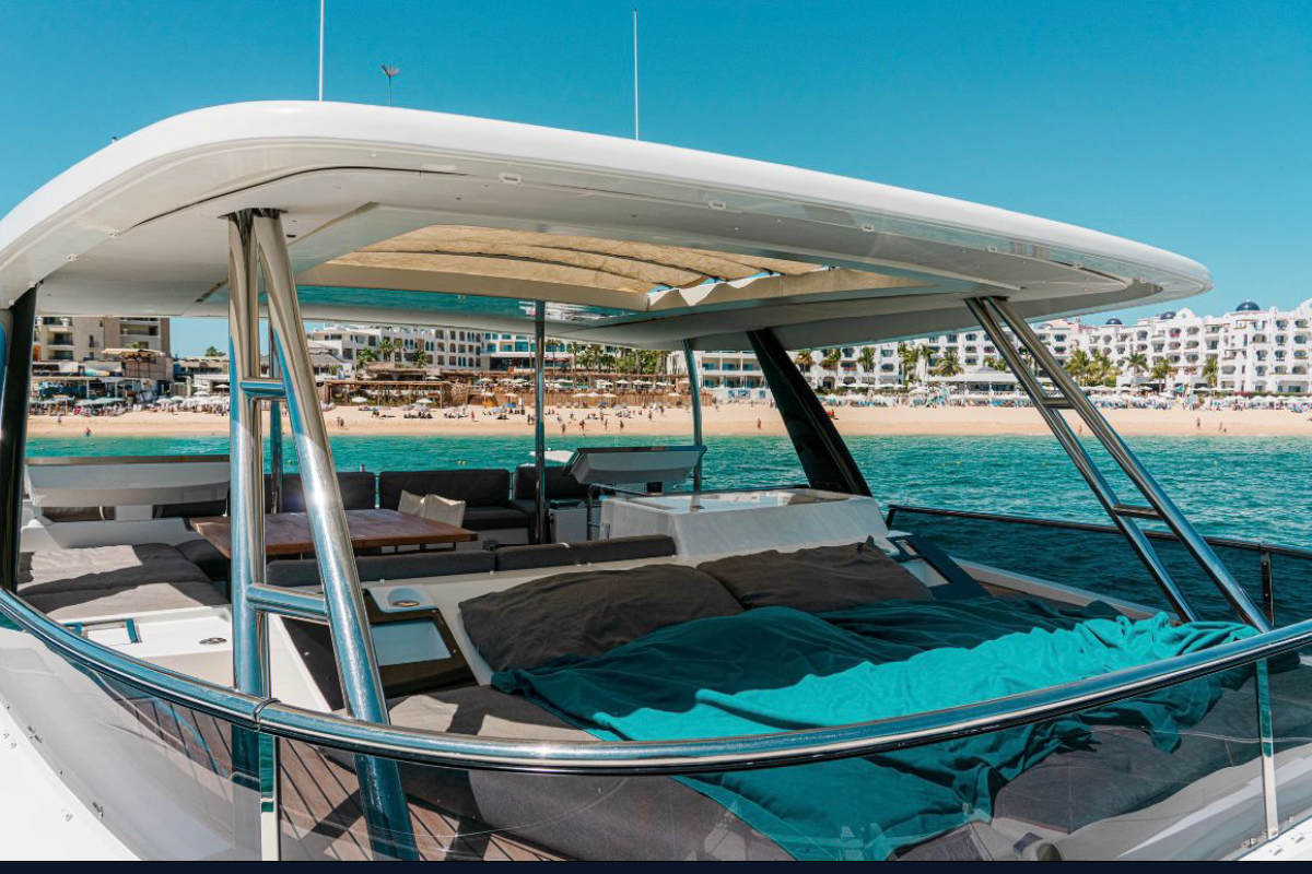 The lounge deck of a luxury catamaran in Cabo San Lucas with Medano Beach behind it
